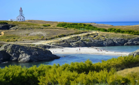Kystlandskab nær Saint-Philibert, Bretagne, Frankrig, med fyrtårn, strand og frodig grøn vegetation.