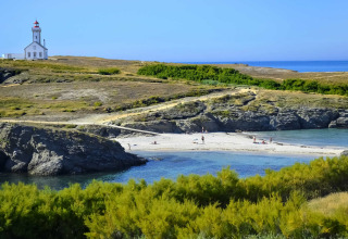 Paesaggio costiero vicino a Saint-Philibert, Bretagna, Francia, con faro, spiaggia e vegetazione rigogliosa.
