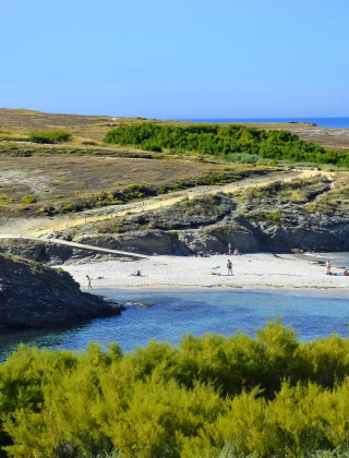 Paesaggio costiero vicino a Saint-Philibert, Bretagna, Francia, con faro, spiaggia e vegetazione rigogliosa.