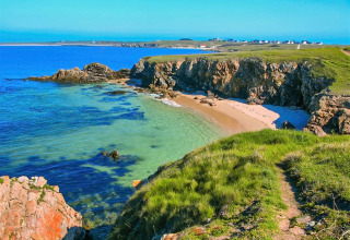 Kustlandschap bij Flower Camping Le Kerarno in Bretagne, Frankrijk met rotsen, strand en blauwe zee.