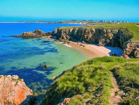 Vista costiera al Flower Camping Le Kerarno in Bretagna, Francia, con scogliere, spiaggia sabbiosa e mare blu.