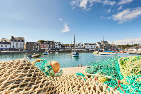 Vista di un porto vicino a Saint-Philibert in Bretagna, con reti da pesca, barche a vela e case tipiche.