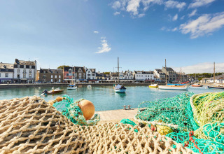 Zicht op een haven nabij Saint-Philibert in Bretagne, met vissersnetten, zeilboten en charmante huizen.