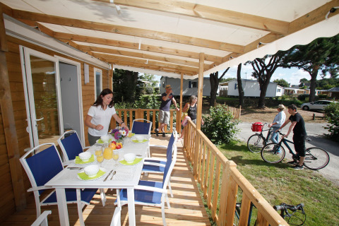 Eine Familie bereitet eine Mahlzeit auf der Terrasse eines Mobilheims vor, während andere Rad fahren.