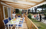 Eine Familie bereitet eine Mahlzeit auf der Terrasse eines Mobilheims vor, während andere Rad fahren.