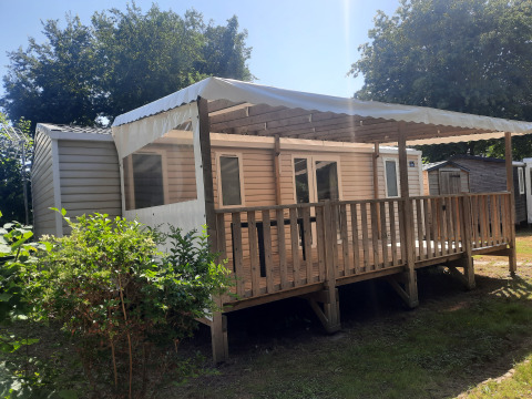 Vue extérieure de la Comfort stacaravan 32m2 avec terrasse en bois couverte et garde-corps, sous le soleil.