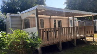 Vue extérieure de la Comfort stacaravan 32m2 avec terrasse en bois couverte et garde-corps, sous le soleil.