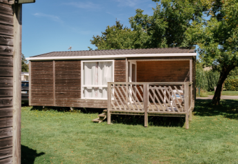 Casa mobile Comfort Stacaravan 22m2 con terrazza in legno, immersa nel verde e circondata da alberi.