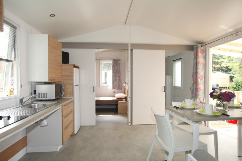 Modern mobile home Comfort Stacaravan PMR 29m2 at Flower Camping Le Kerarno with kitchen and dining area.