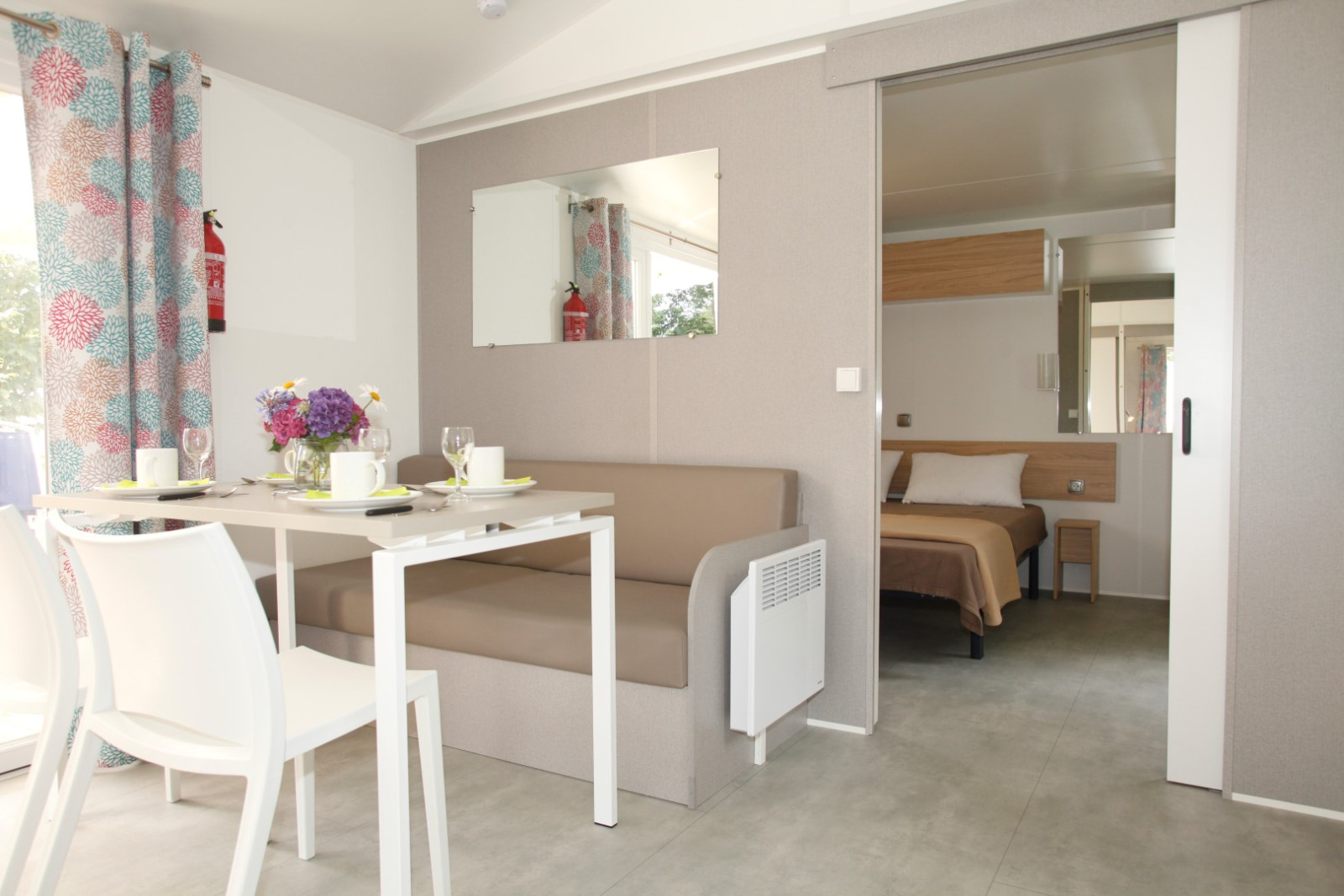 Interieur van Comfort Stacaravan PMR 29m2 met eettafel en slaapkamer op Flower Camping Le Kerarno, Frankrijk.