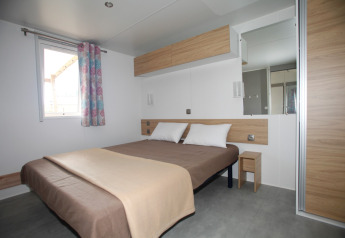 Chambre dans Comfort Stacaravan PMR 29m2 au Flower Camping Le Kerarno, France, avec lit double et décoration moderne.