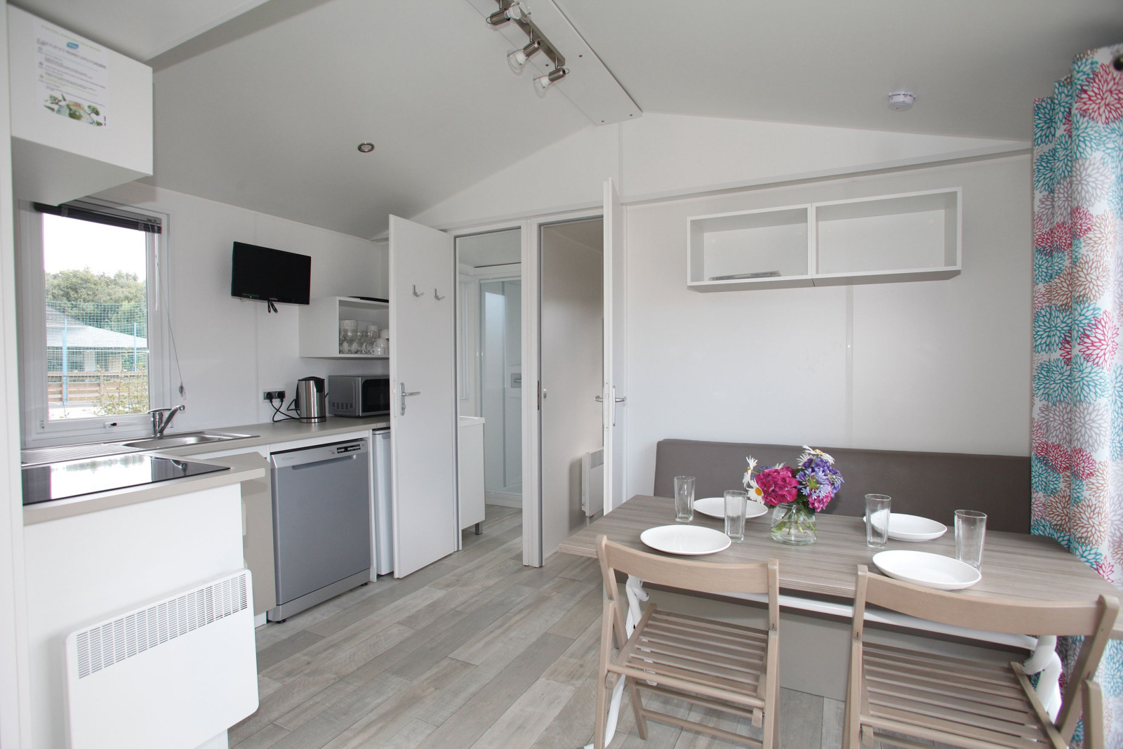 Moderne keuken en eethoek in een mobiel huis, met tafel voor vier en vaas bloemen als decoratie.