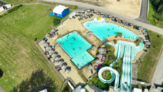 Luchtfoto van het zwembadcomplex, waterglijbanen en zonnebedden bij Flower Camping Le Vorlen in Bretagne.