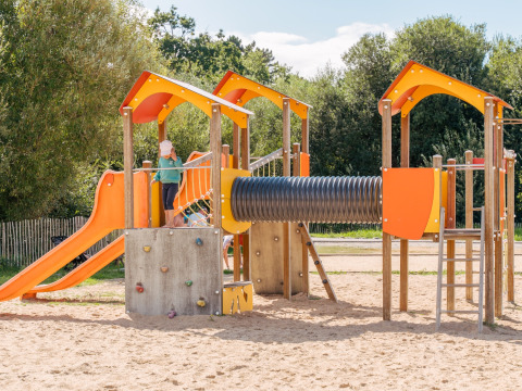 Parco giochi con scivoli, parete da arrampicata e sabbia al Flower Camping Le Vorlen in Bretagna, Francia.