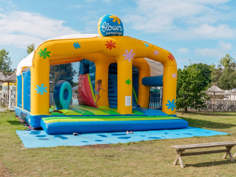 Kinderen spelen op een kleurrijk springkasteel bij Flower Camping Le Vorlen vakantiepark in Bretagne, Frankrijk.