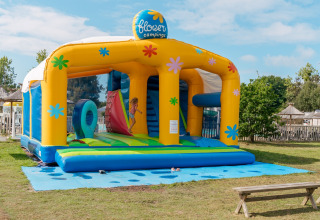 Niños jugando en un castillo inflable colorido en Flower Camping Le Vorlen, un parque vacacional en Bretaña, Francia.