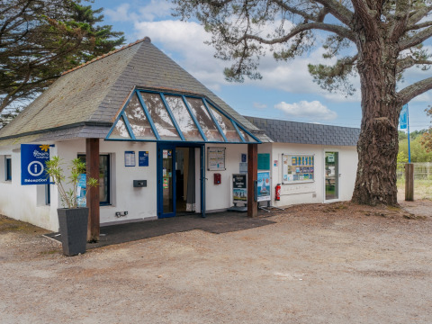 Receptionen på Flower Camping Le Vorlen feriepark i Bretagne, Frankrig med træ og informationstavler.