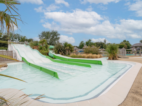 Water slides and a children's pool at Flower Camping Le Vorlen holiday park in Brittany, France on a sunny day.