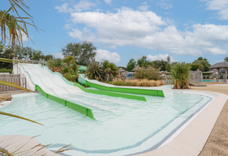 Water slides and a children's pool at Flower Camping Le Vorlen holiday park in Brittany, France on a sunny day.