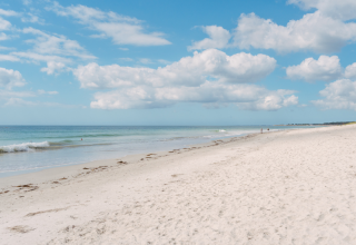 Tranquil sandy beach with blue sea and sky at Flower Camping Le Vorlen holiday park in Brittany, France.