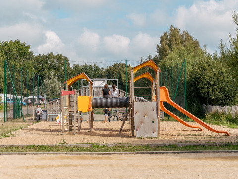 Parco giochi con scivolo e parete da arrampicata al Flower Camping Le Vorlen, villaggio vacanze in Bretagna, Francia.