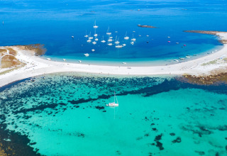 Aerial view of boats and sandy beach at Flower Camping Le Vorlen holiday park in Brittany, France.