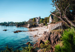 Costa panoramica presso Flower Camping Le Vorlen in Bretagna, Francia, con spiaggia, rocce e case eleganti.