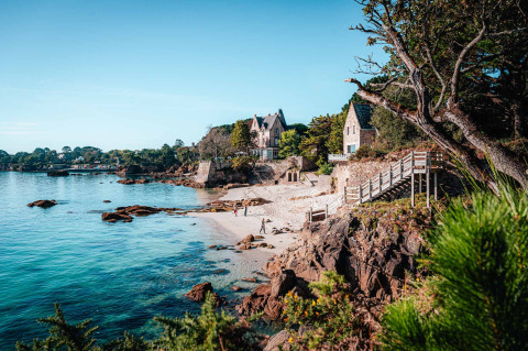 Pittoreske kust aan Flower Camping Le Vorlen in Bretagne, Frankrijk, met strand, kliffen en villa’s.