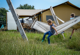Twee kinderen spelen op een hangmat voor tenten bij Holiday Park Mölke in het groene Overijssel, Nederland.