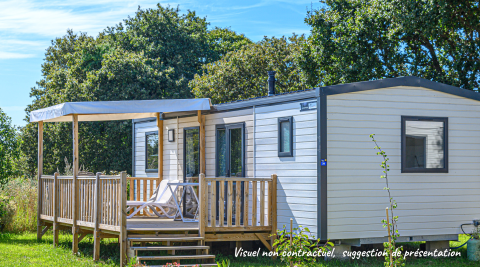 Casa mobile Premium Stacaravan con 2 camere, terrazza e lettini, immersa nel verde sotto il cielo azzurro.