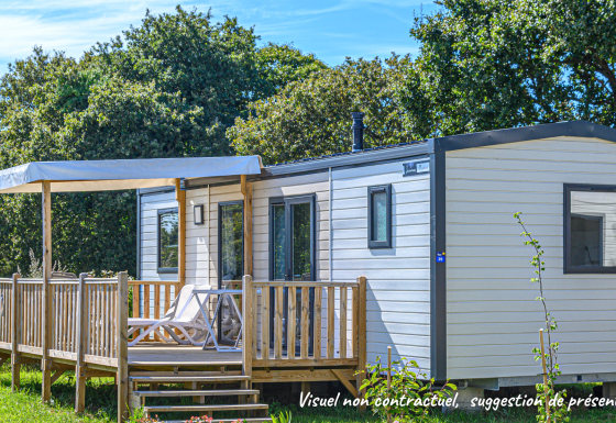Casa mobile Premium Stacaravan con 2 camere, terrazza e lettini, immersa nel verde sotto il cielo azzurro.