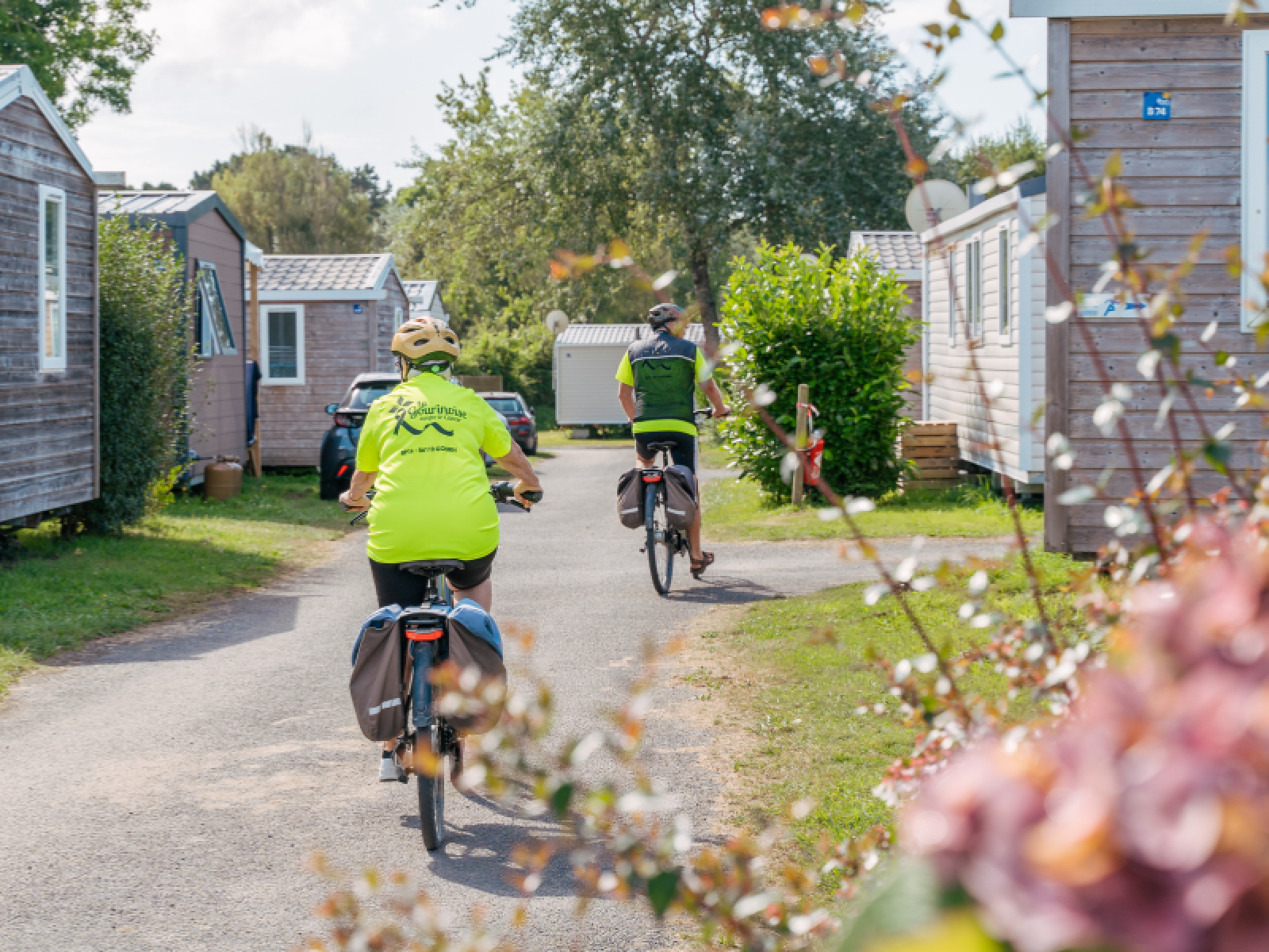Twee mensen fietsen tussen stacaravans bij Standard Wooden Mobile Home op Flower Camping Le Vorlen in Frankrijk.