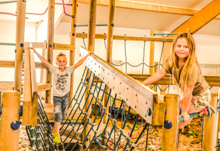 To børn leger på en indendørs legeplads med træ- og netkonstruktioner i Holiday Park Mölke, Holland.