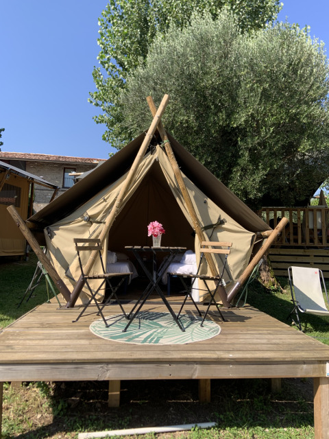 Tente safari junior au Sivinos Camping Boutique en Italie, avec terrasse en bois, table et chaises dehors.