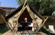Safari-Juniorzelt bei Sivinos Camping Boutique in Italien mit Holzterrasse, Tisch und Stühlen davor.