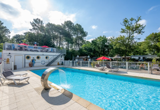 Piscina al aire libre con tumbonas y fuente en Flower Camping La Canadienne, Nouvelle-Aquitaine, Francia.