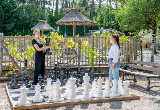 Dos mujeres juegan al ajedrez con piezas gigantes al aire libre en Flower Camping La Canadienne, Francia.