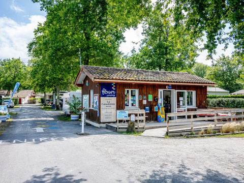Indgangen til Flower Camping La Canadienne, en ferielejrplads omgivet af træer i Nouvelle-Aquitaine, Frankrig.