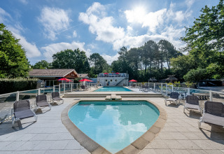 Zona de piscina al aire libre con tumbonas en Flower Camping La Canadienne, Nouvelle-Aquitaine, Francia.