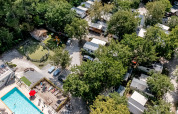 Aerial view of Flower Camping La Canadienne with pool, playground, mobile homes, and abundant trees.