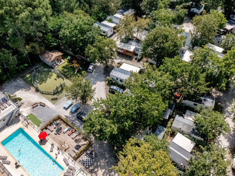 Aerial view of Flower Camping La Canadienne with pool, playground, mobile homes, and abundant trees.