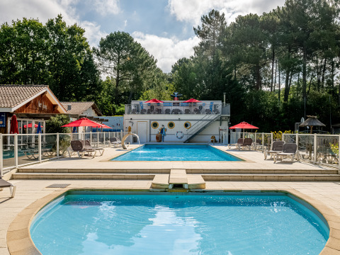 Zona de piscina y solárium en Flower Camping La Canadienne, un parque vacacional en Nueva Aquitania, Francia.
