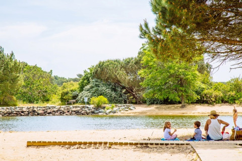 Una famiglia si rilassa sulla riva sabbiosa del fiume tra alberi verdi vicino ad Arès, Nouvelle-Aquitaine.