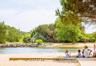 Familie genießt einen Tag am Sandstrand mit Fluss und Bäumen in der Nähe von Arès, Nouvelle-Aquitaine.