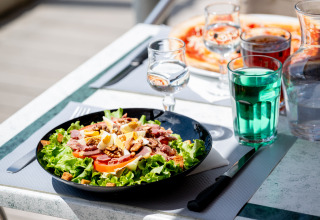 Insalata fresca e bevanda verde su un tavolo all'aperto al Flower Camping La Canadienne, Nouvelle-Aquitaine, Francia.