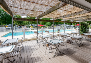 Espace repas extérieur avec vue sur la piscine au Flower Camping La Canadienne, Nouvelle-Aquitaine, France.
