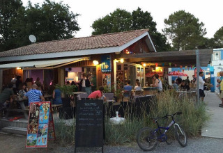 Avondbeeld van een levendige bar op Flower Camping La Canadienne in Nouvelle-Aquitaine, Frankrijk.