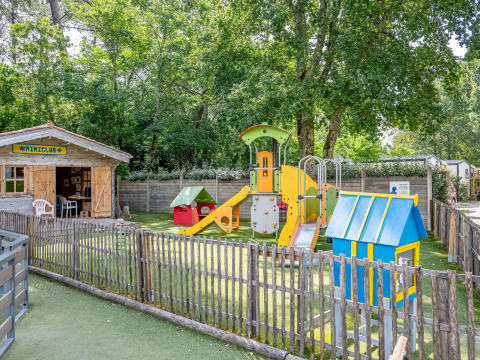 Speelplein met kleurrijke speeltoestellen en miniclubhuis bij Flower Camping La Canadienne, Nouvelle-Aquitaine.