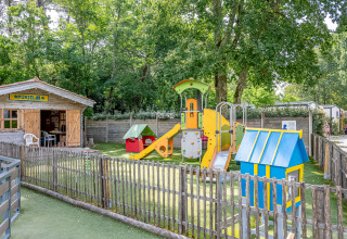 Spielplatz mit buntem Spielgerät und Miniclubhaus im Flower Camping La Canadienne, Nouvelle-Aquitaine, Frankreich.