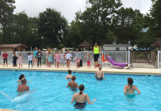 Kinderen en volwassenen nemen deel aan groepsactiviteiten bij het zwembad op Flower Camping La Canadienne in Frankrijk.